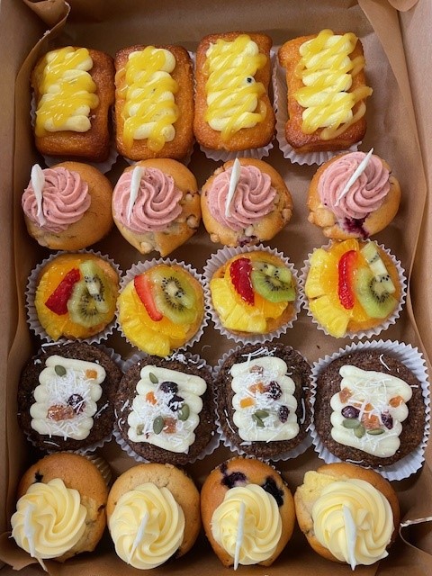 A box of assorted muffins, iced fingers and carrot squares